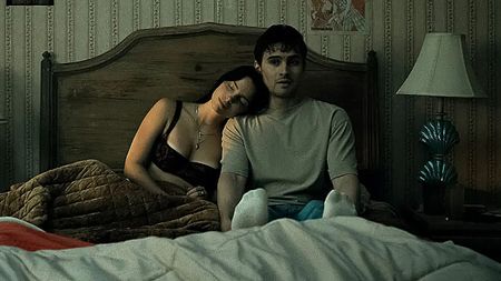Nikki leaning on Bear as they sit in bed together in Obsession
